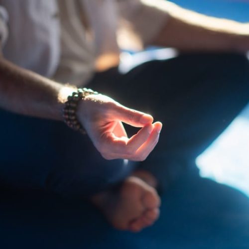 Close-up of meditating mans hands. Barefoot man sitting in lotus pose with smoke around making sign with fingers. Hobby, spirituality, health concept